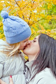 Photo of kissing mother and daughter in autumn