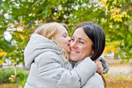 Photo of kissing mother and daughter in autumn