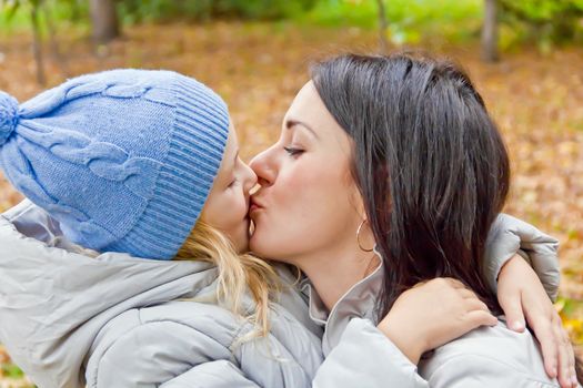 Photo of kissing mother and daughter in autumn