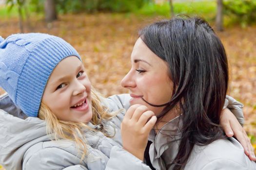 Photo of smiling mother and daughter in autumn