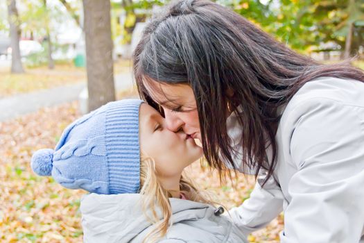 Photo of kissing mother and daughter in autumn