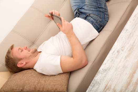 A young man with a Tablet PC on the Sofa.