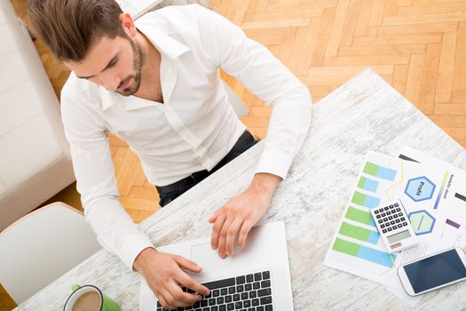 A young man checking his business statistics at home