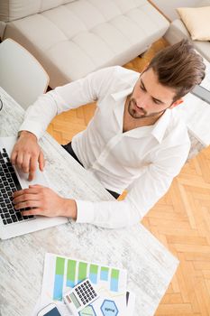 A young man checking his business statistics at home