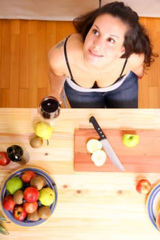 A young adult woman cutting fruits in the kitchen.