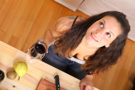 A young adult woman cutting fruits in the kitchen.