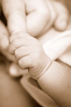 Sepia new-born baby keeps for a  mother's finger.