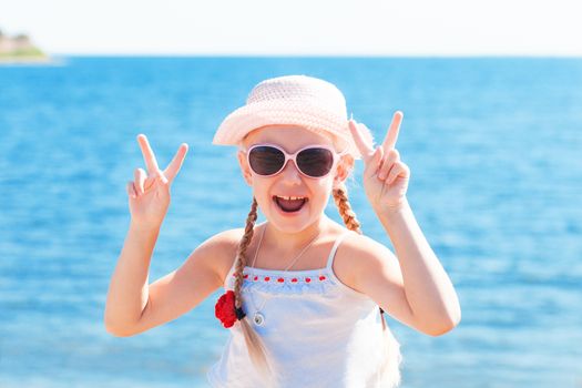 girl showing sign victory with fingers near sea