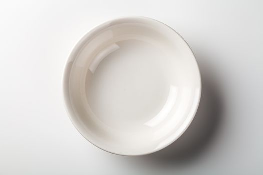 White plate on white background with shadow. Top view 