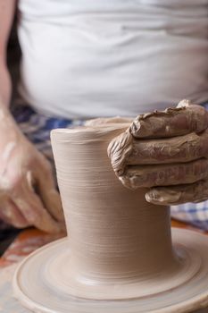 Hands of a potter, creating an earthen jar on the circle