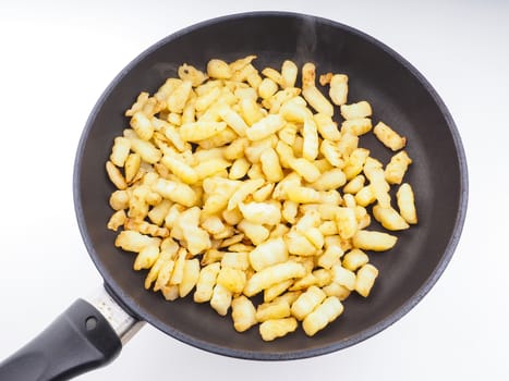 Frying chopped potatoes in a fry pan isolated