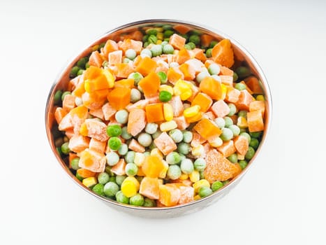 Frozen carrots, maize and peas, thawing in a steel bowl