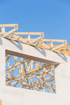 New residential construction roof home framing against a blue sky