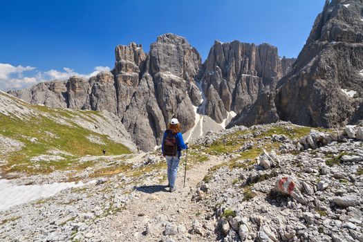 hiker on footpath  in Sella mountain, on background Mezdi valley and Piz da Lech peak, south Tyrol, Italy