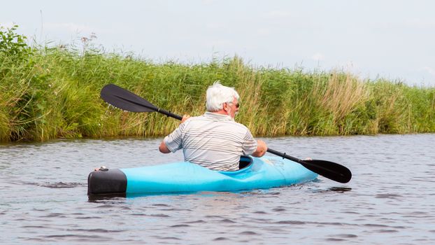 Man paddling in a blue kayak in the Netherlands