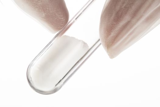 Close up of white powder in test tube being held by fingers
