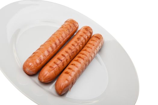 Three delicious wurstel on a white plate over white background