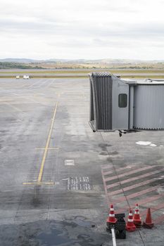 Unmanned jet bridge with empty airport landing area in the background.