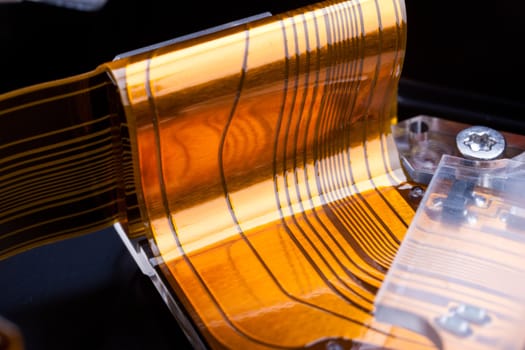 macro shot of a golden flat wire connecting an hard disk to his circuit board