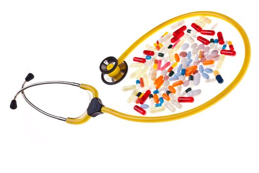 many pills and capsules over white surrounded by a yellow stethoscope