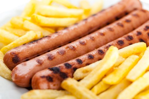 three delicious wurstel on a white plate with french fries