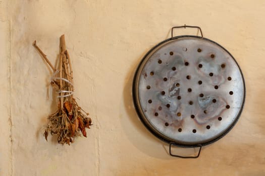 Dryed Chili peppers and an old pan on a dirty wall. Mediterranean culture.