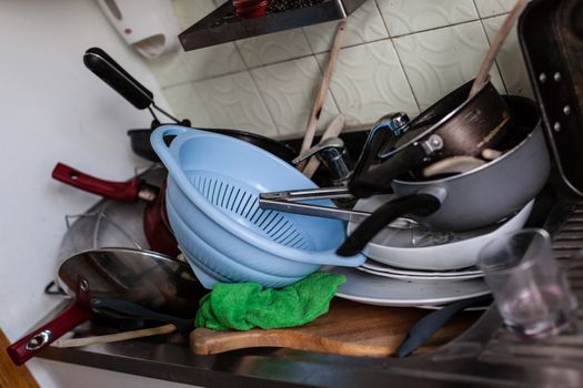 a lot of dirty pans, glasses and other kitchen utensils in a sink