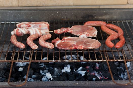 Several type of meats being cooked on a barbecue