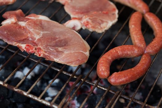 Several type of meats being cooked on a barbecue