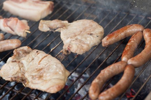 Several type of meats being cooked on a barbecue