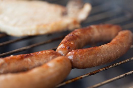 Several type of meats being cooked on a barbecue