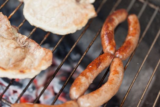 Several type of meats being cooked on a barbecue