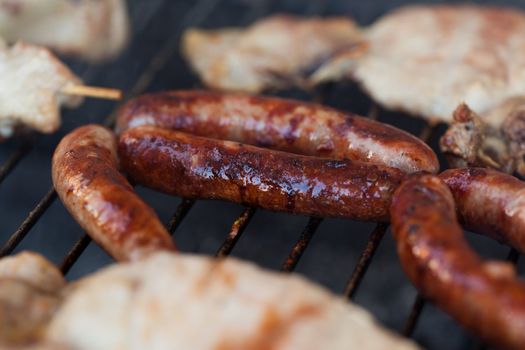 Several type of meats being cooked on a barbecue