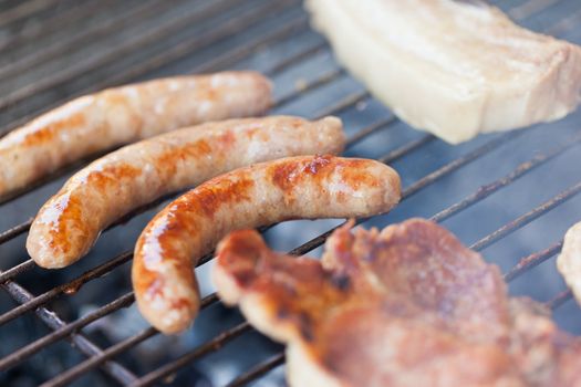 Several type of meats being cooked on a barbecue