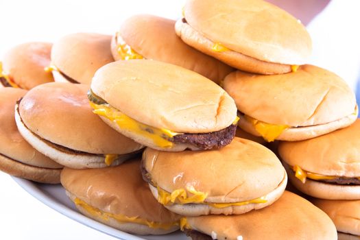 A plate full of cheesburgers isolated on a white background holded by hands