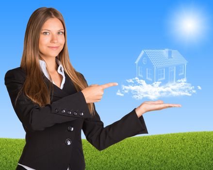 Businesswoman hold house of clouds. Green grass and blue sky as backdrop