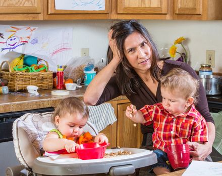 Stressed out mother in kitchen with her babies