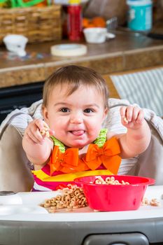 Baby girl eats breakfast in her highchair