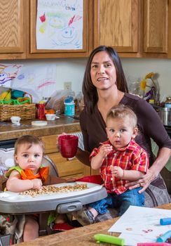 A mother in the kitchen poses with babies