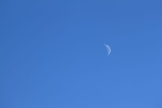 The moon in front of a beautiful blue sky