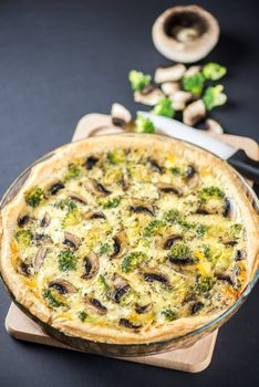 Delicious mushroom quiche on black background with knife