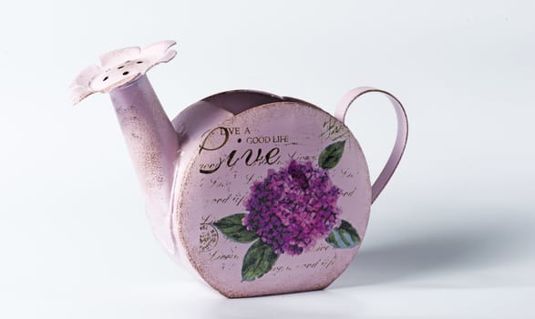 Purple metal watering can on white background