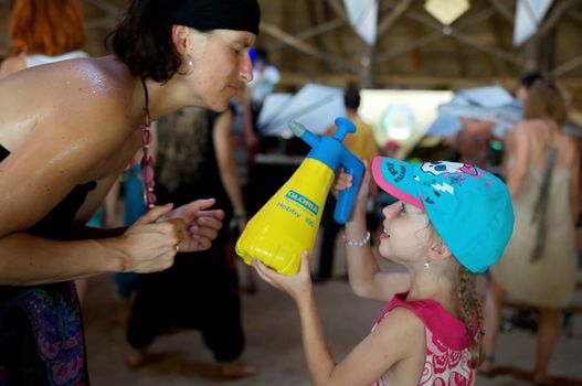 OZORA, HUNGARY - AUGUST 01: Little girl spray water on a woman on Ozora Festival, one of the greatest psychedelic music gathering in Euorpe. Ozora, Hungary, Europe August 01, 2014.
