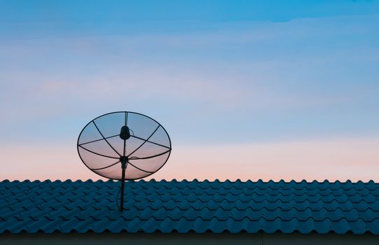 Silhouetted satellite dish on the roof in sunset sky