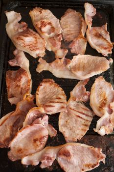 Rashers of delicious grilled bacon on a hot griddle in a close up background image from above