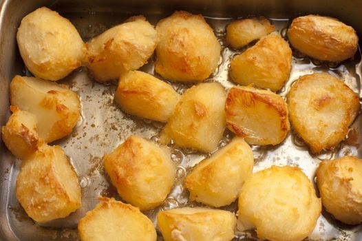 Catering background of delicious golden roast potatoes in a hot roasting pan fresh from the oven