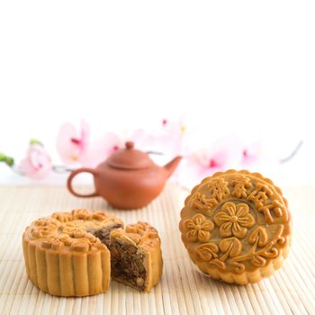 Chinese mid autumn festival foods with blank copy space. Traditional mooncakes on table setting with teapot. The Chinese words on the mooncakes means vegetarian low sugar assorted fruits nuts, not a logo or trademark.