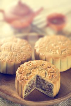 Retro vintage style Chinese mid autumn festival foods. The Chinese words on the mooncakes means assorted fruits nuts, not a logo or trademark. Traditional mooncakes on table setting with teacup. 