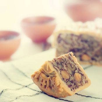 Retro vintage style Chinese mid autumn festival foods. Traditional mooncakes on table setting with teacup. The Chinese words on the mooncakes means assorted fruits nuts, not a logo or trademark