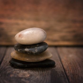 Pebbles stock on wooden background, in low light setting with vintage filter.